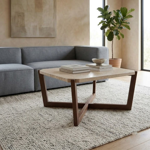 Square travertine coffee table styled with books and ceramic bowl