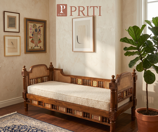 A traditional dark wood daybed, or diwan, featuring intricate carvings, turned wooden posts, and woven cane panels on the back and armrests.