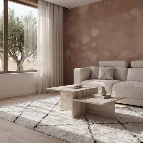 Two-tier travertine coffee table shown with sofa and sheer curtains